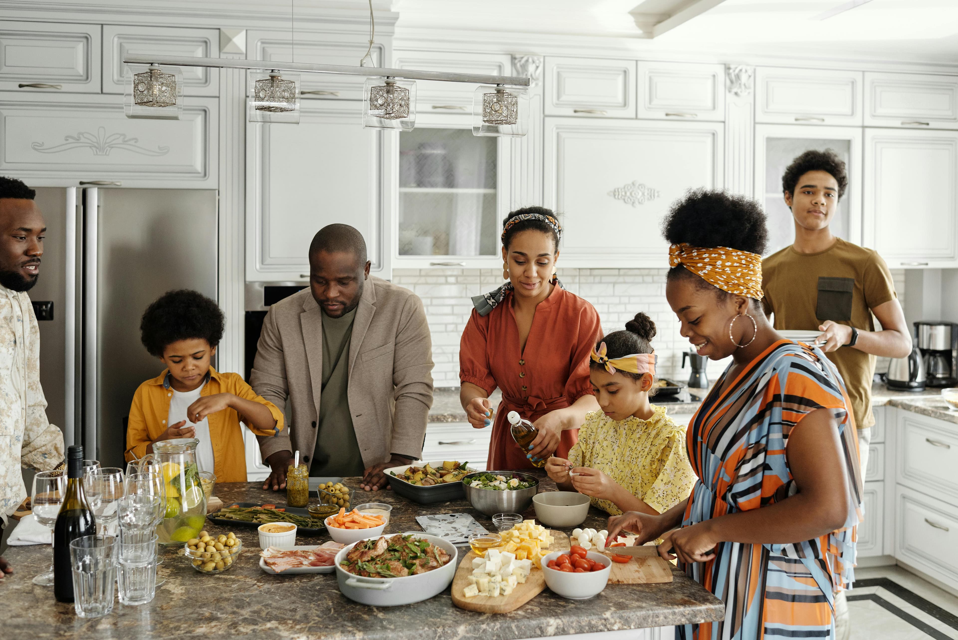 A family of 7 peoples with 2 kids in the kitchen island preparing food island 
