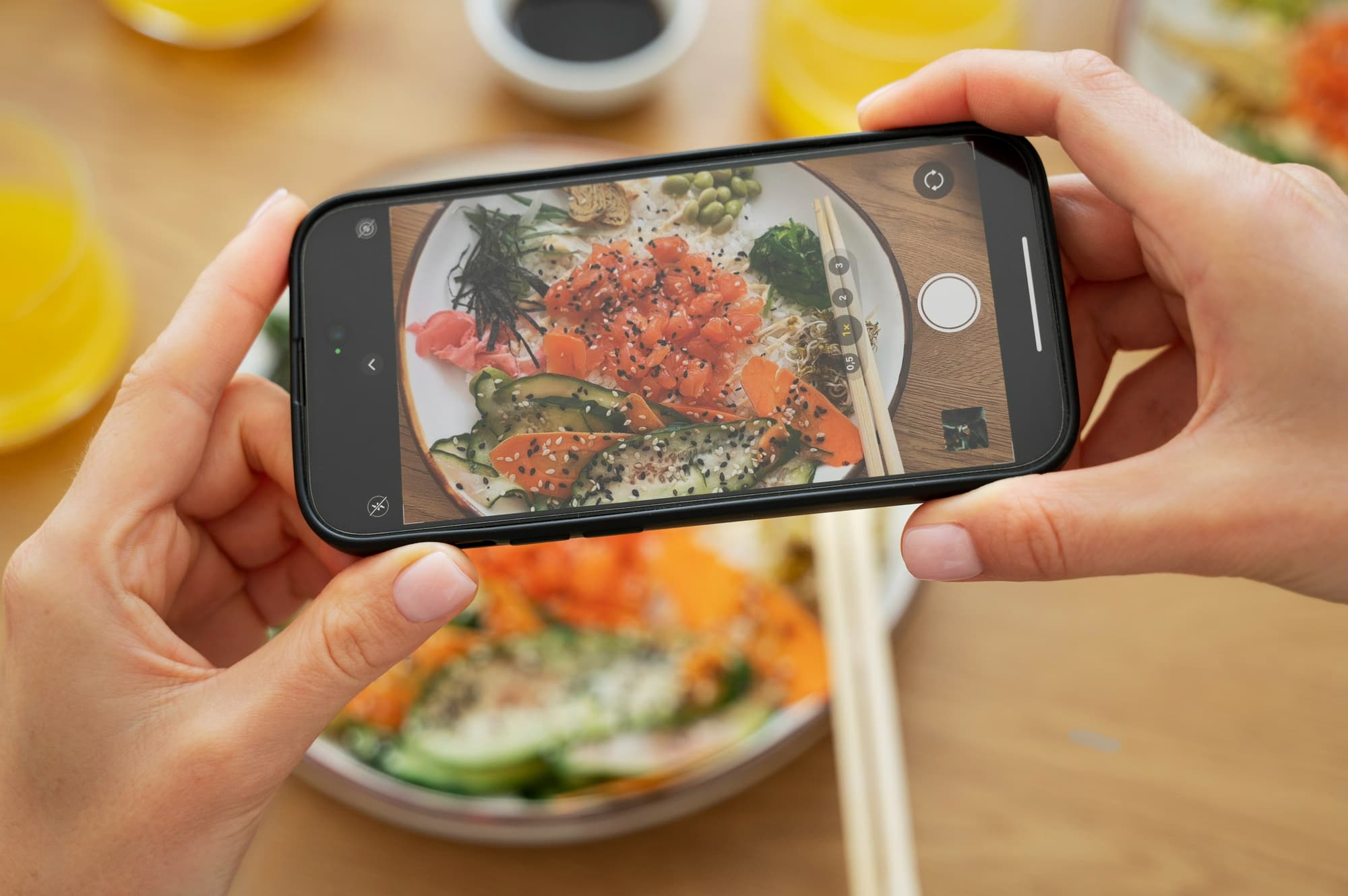 Smartphone capturing a bowl of food on a table using natural light for food photography at home.