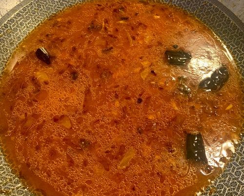 Water added to tempered spices in a pan. 