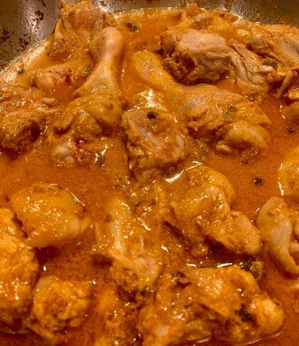 Partially cooked chicken pieces in orange curry