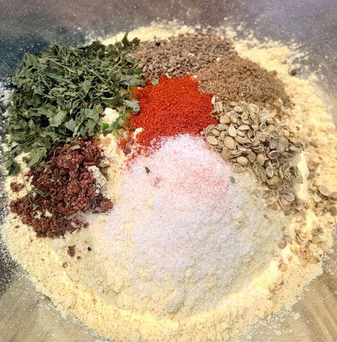 Powdered spices and gram flour in a mixing bowl. 