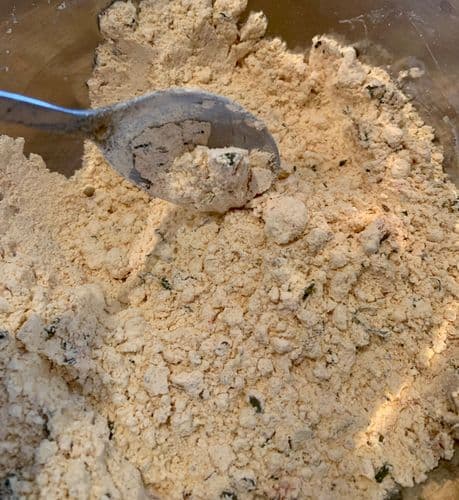 Gram flour mixed with spices in a large mixing bowl with small lumps