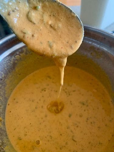 A watery gram flour mixture with medium consistency pouring off a spoon. 