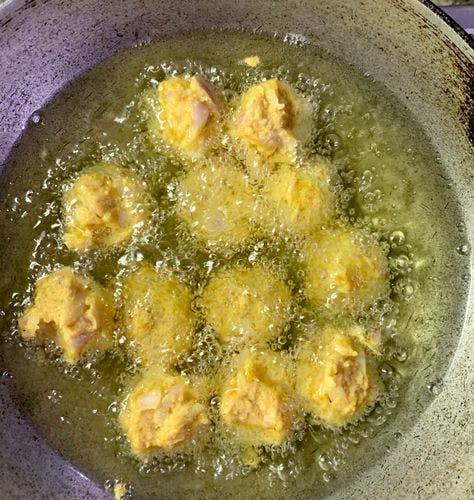 A bunch of fritters being deep-fried in oil