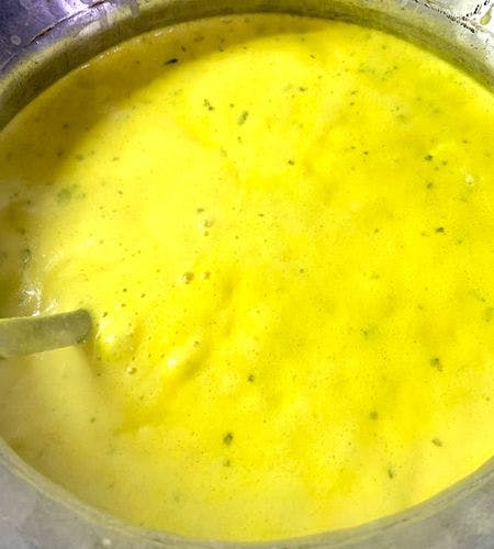 Slightly bubbling yellow kadhi in a pot
