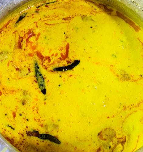 Dry red chillies floating in a pot of kadhi