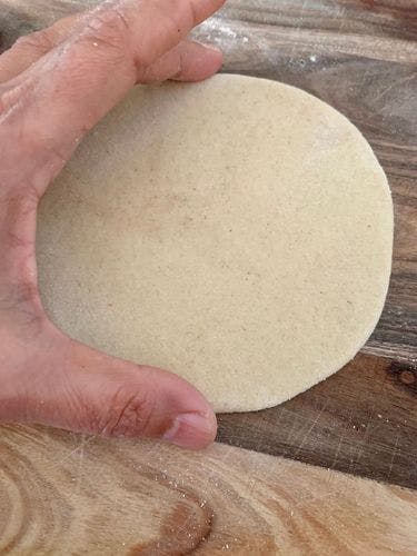 Round rolled dough on a wooden board.