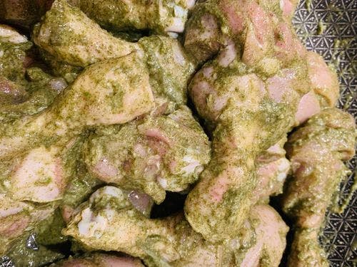 Raw chicken drumsticks mixed with green mint marinade