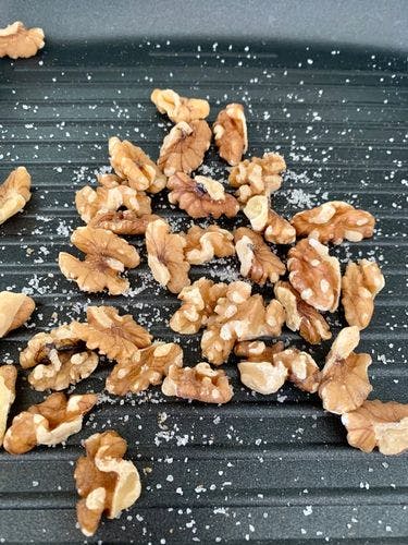 Walnuts sprinkled with salt on a grill pan