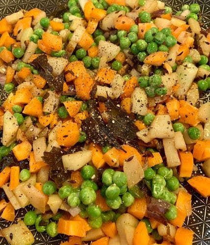 A mixture of sago/sabudana pearls, chopped carrots, peas and black pepper in a pan. 