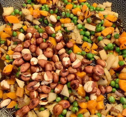 Roasted peanuts with chopped veggies in a pan.