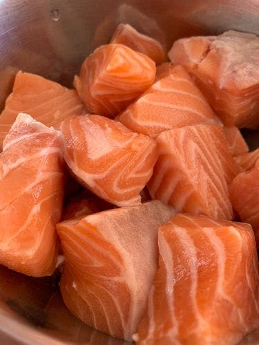 Uncooked salmon pieces in a mixing bowl