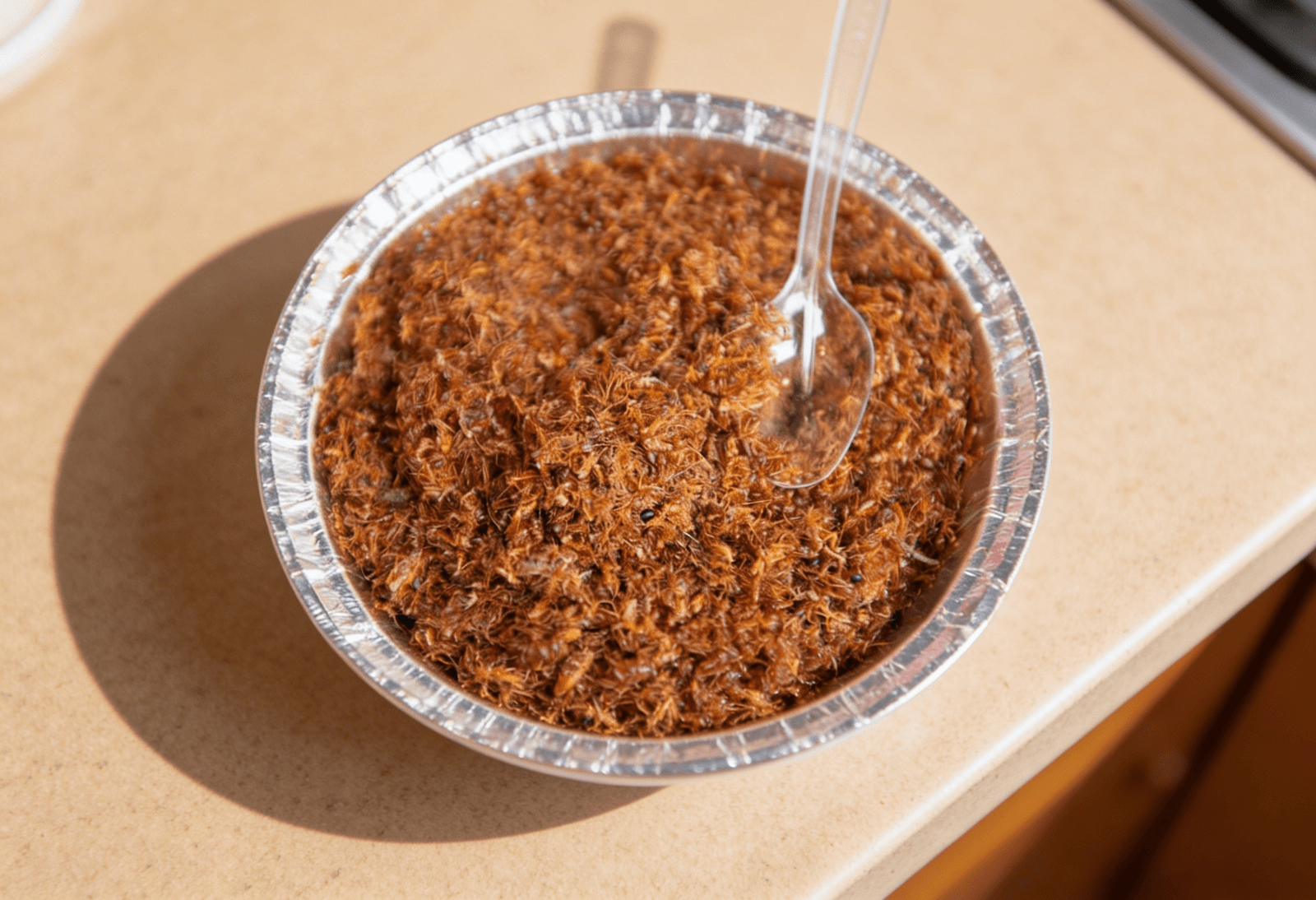counter top view of kai chutney: red weaver ant chutney in a bowl on a light brown counter