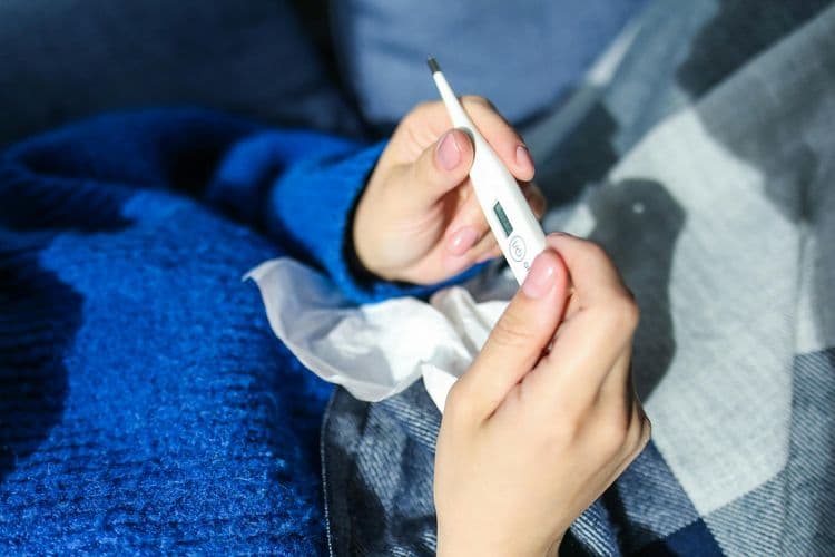 A sick person reads the thermometer to check their temperature. 