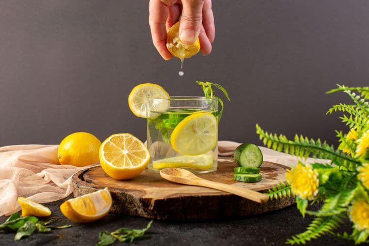 front-view-water-with-lemon-fresh-cool-drink-inside-glass-getting-some-lemon-juice-with-ice-cubes-sliced-lemons-cucumber-dark