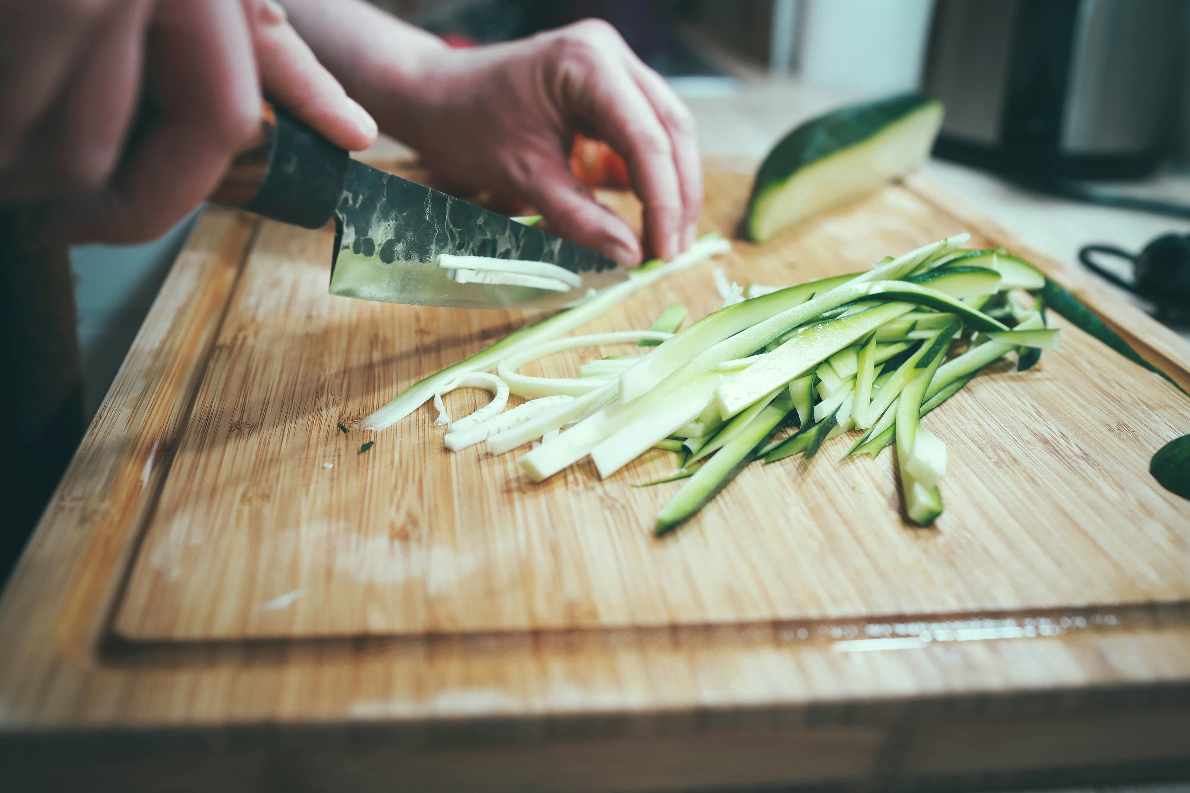 A cucumber being cut in long stripes.