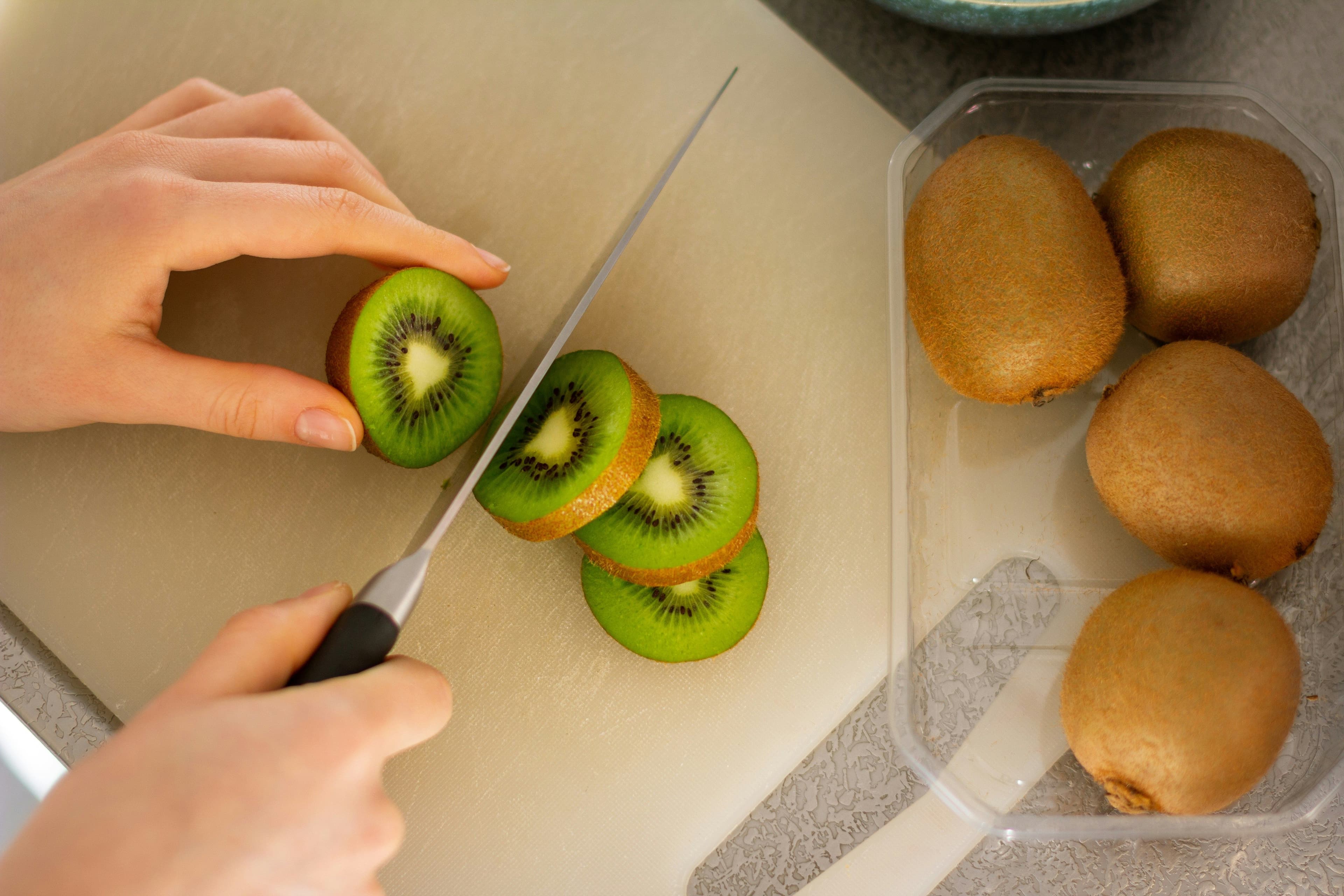 A kiwi being sliced in even round pieces.