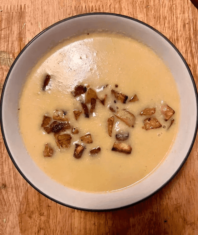A close-up of Creamy Cauliflower Soup with Spicy Potatoes placed as garnish.