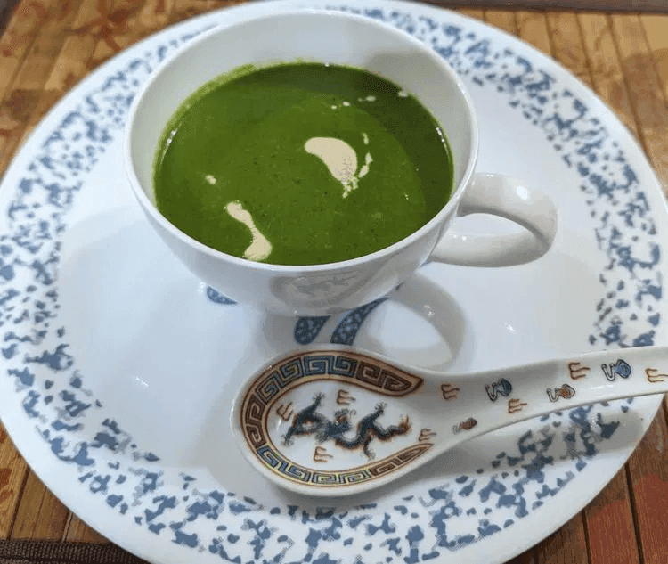 A close-up of spinach soup served in a cup.