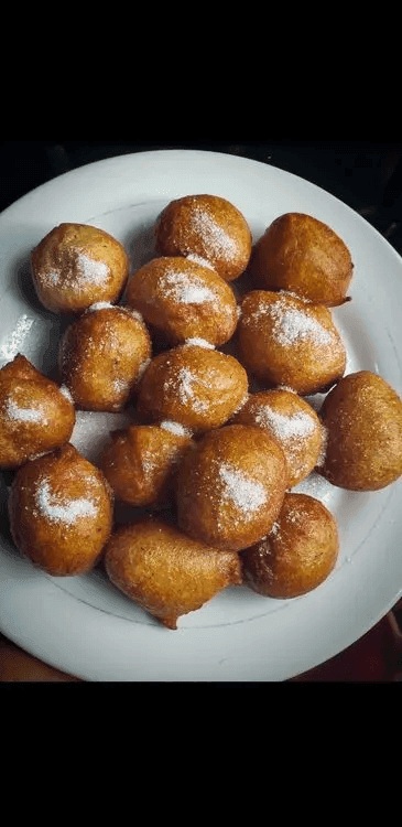 A close-up of a bowl containing several Nigerian puff-puff (fried dough balls)