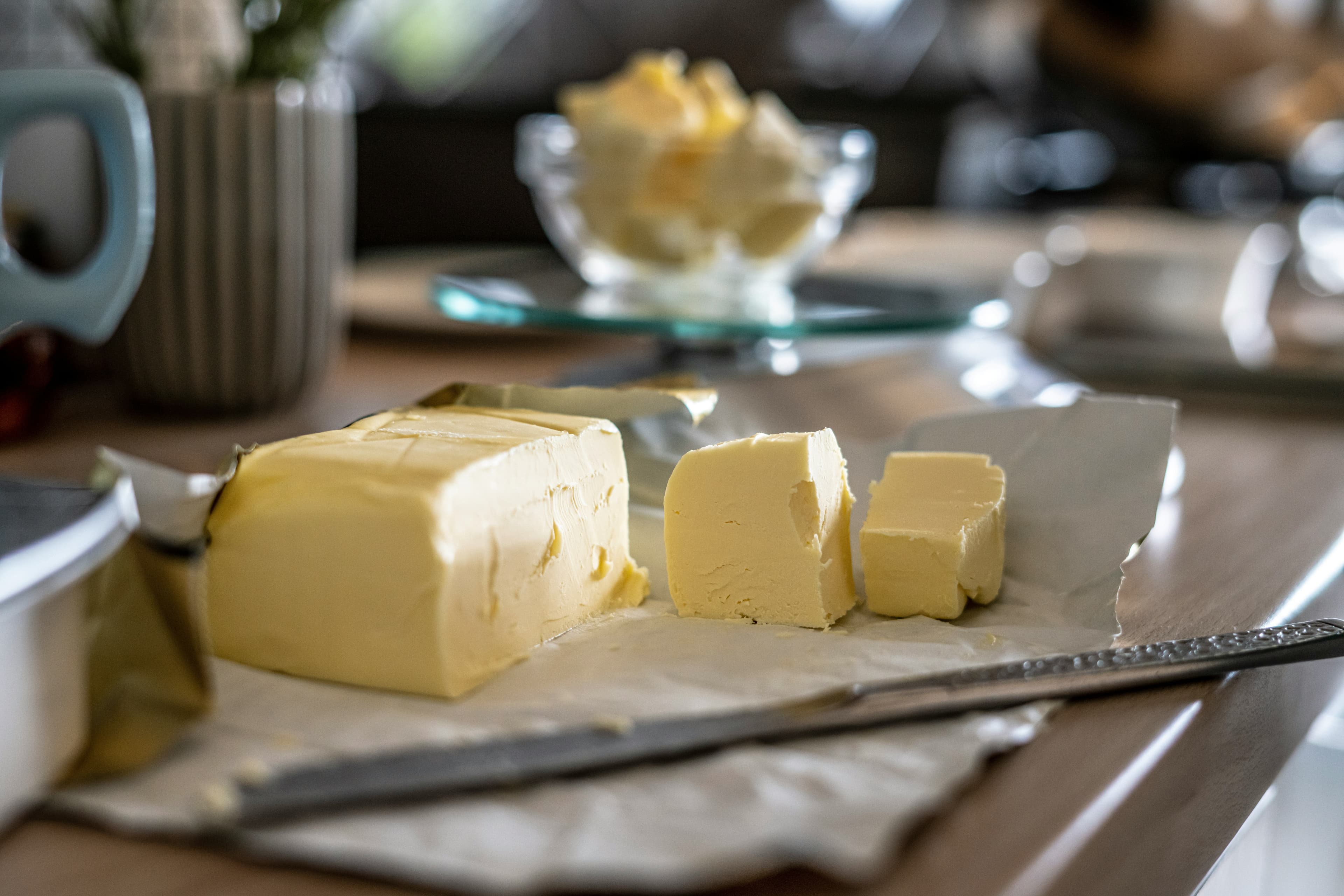 Sliced pieces of butter beside a block of butter with a knife placed by the tray.