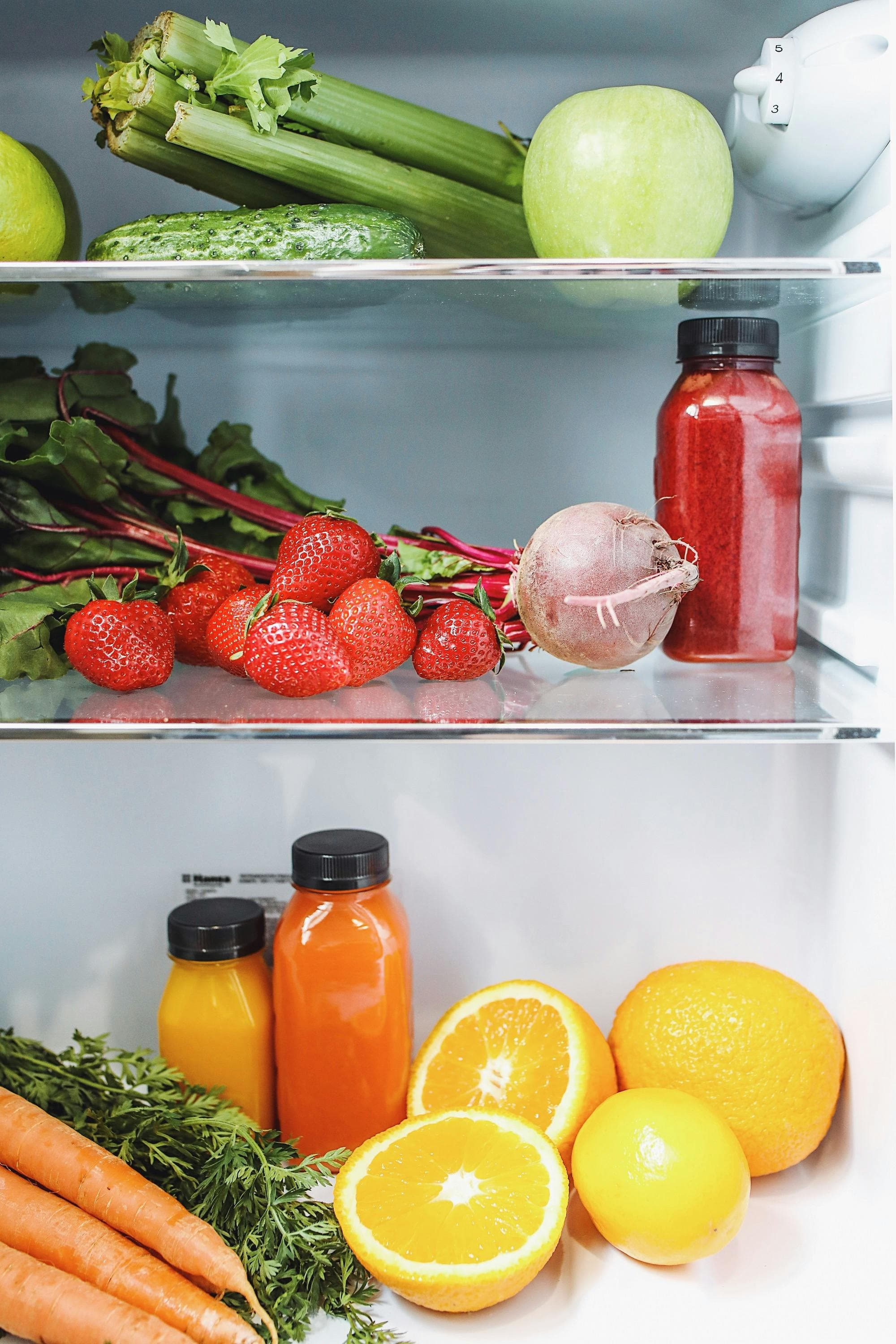 Fruits, vegetables, and juice bottles place in a refrigerator.