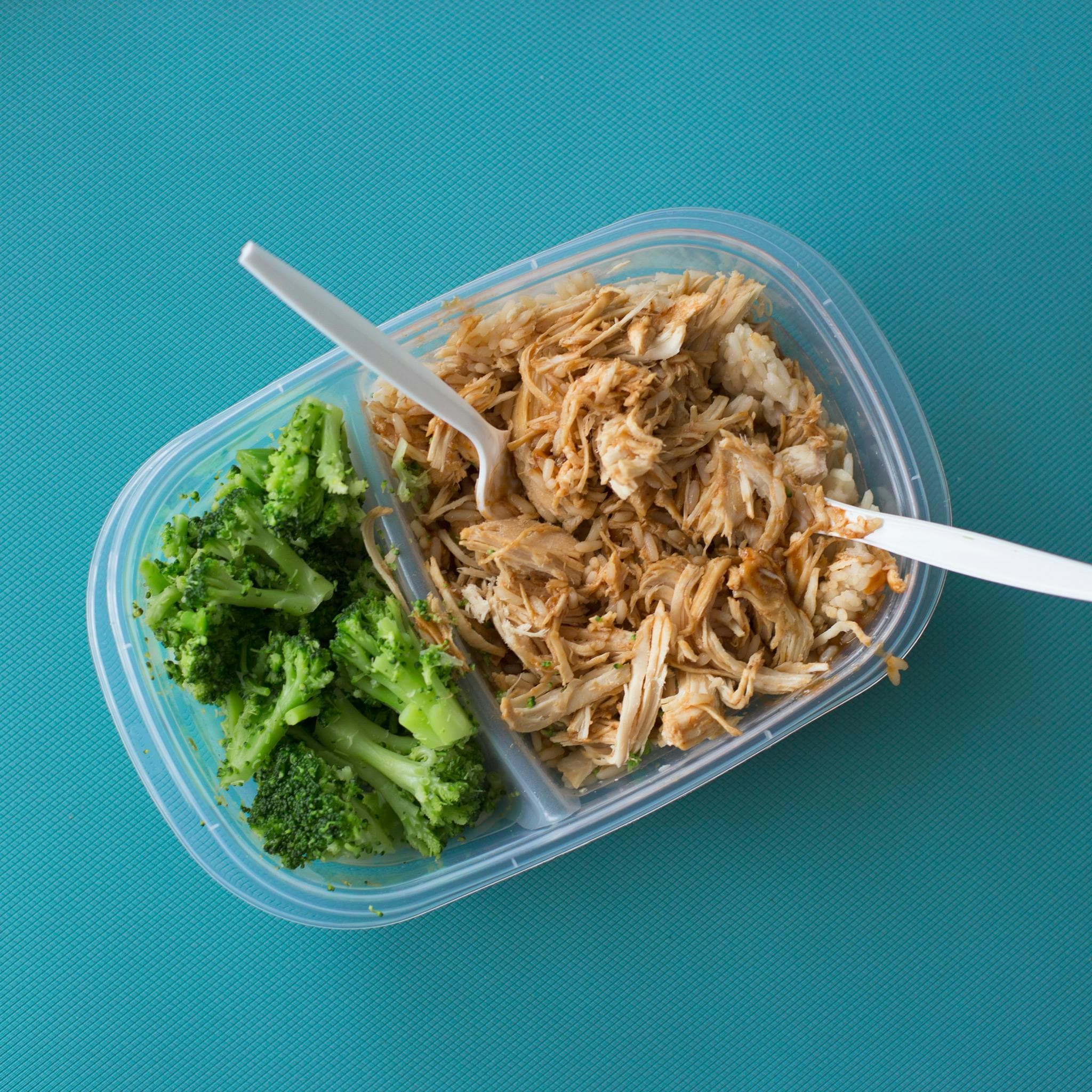 Shredded chicken and steamed broccoli in a lunchbox.