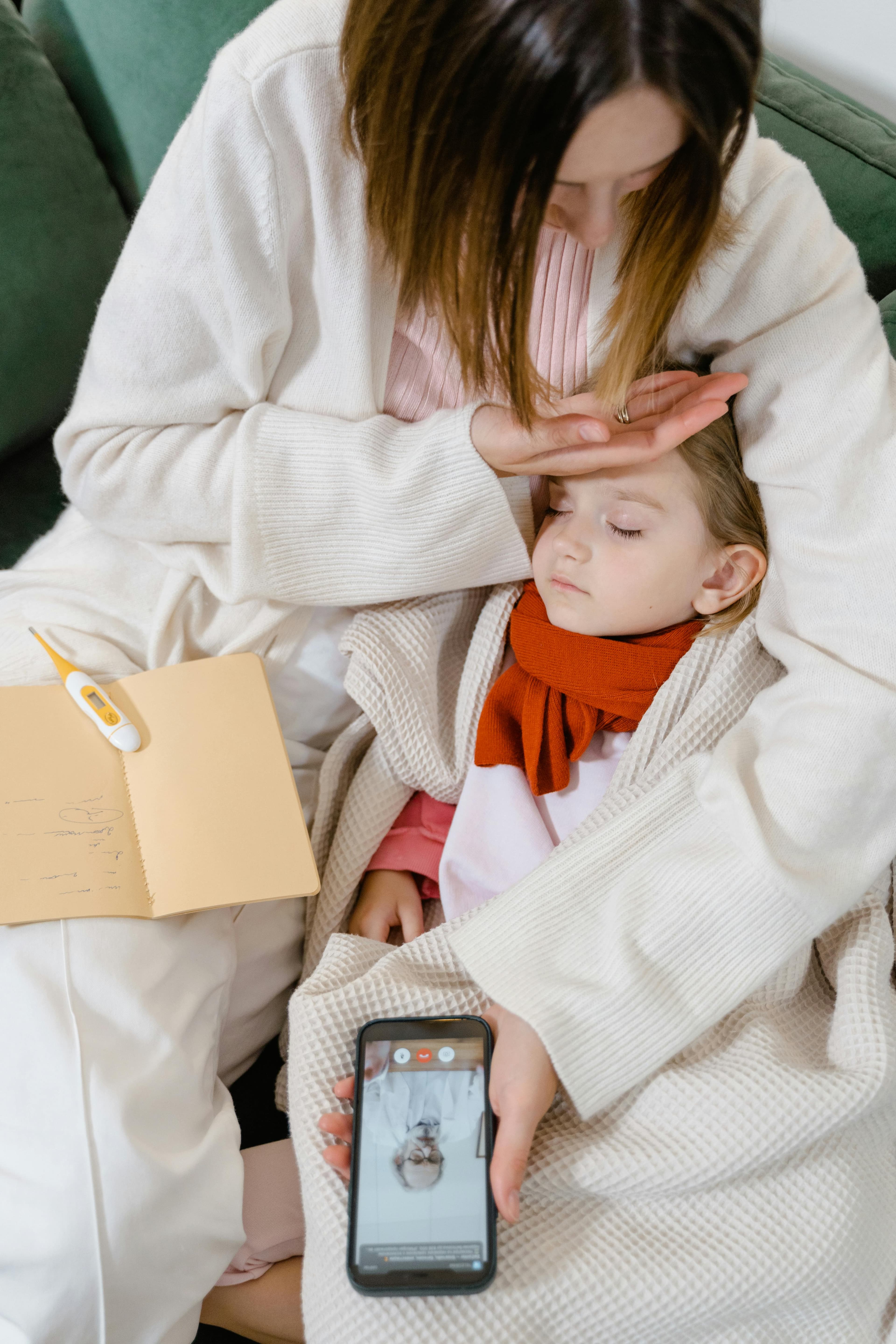A mother checks the temperature of her sick daughter by touching her forehead.