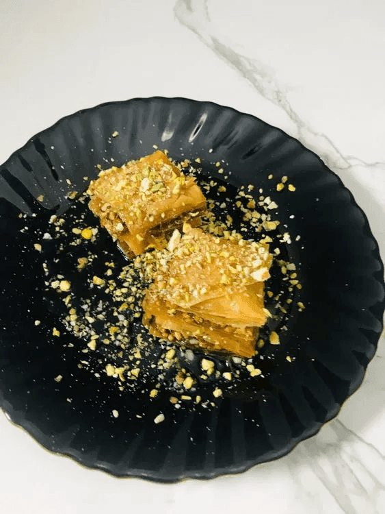 A close-up of a plate containing pieces of pistachio baklava.