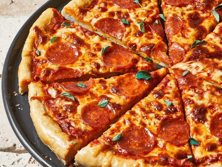 A close-up of a plate containing a whole pizza sliced into equal parts.