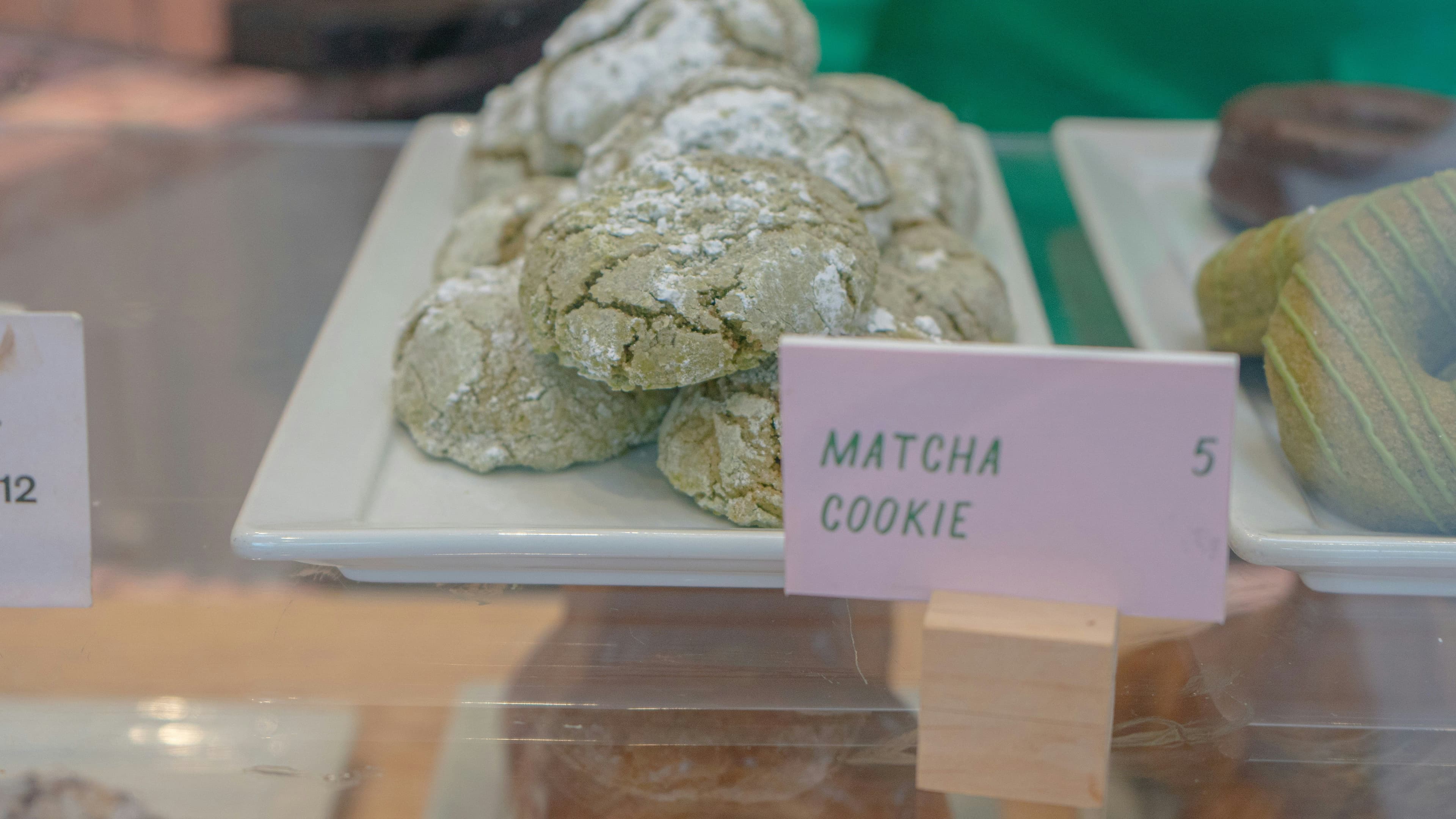 A close-up of matcha cookies on a plate placed behind a glass panel for display.