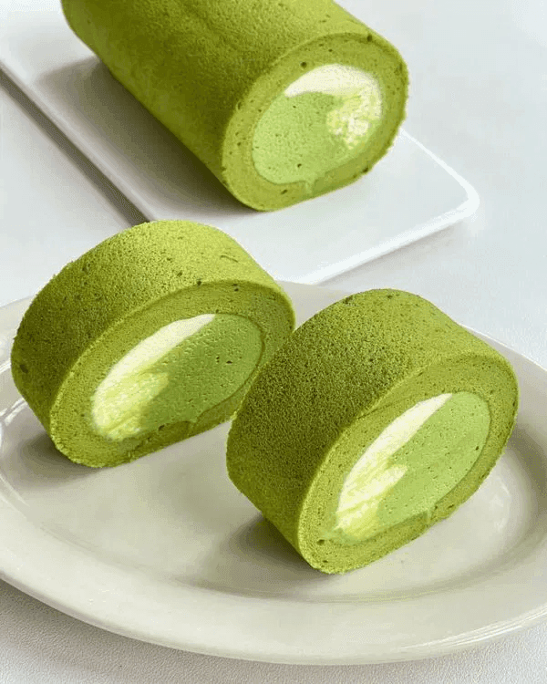Several sliced pieces of Matcha Two-Color Cake Roll served on a plate.