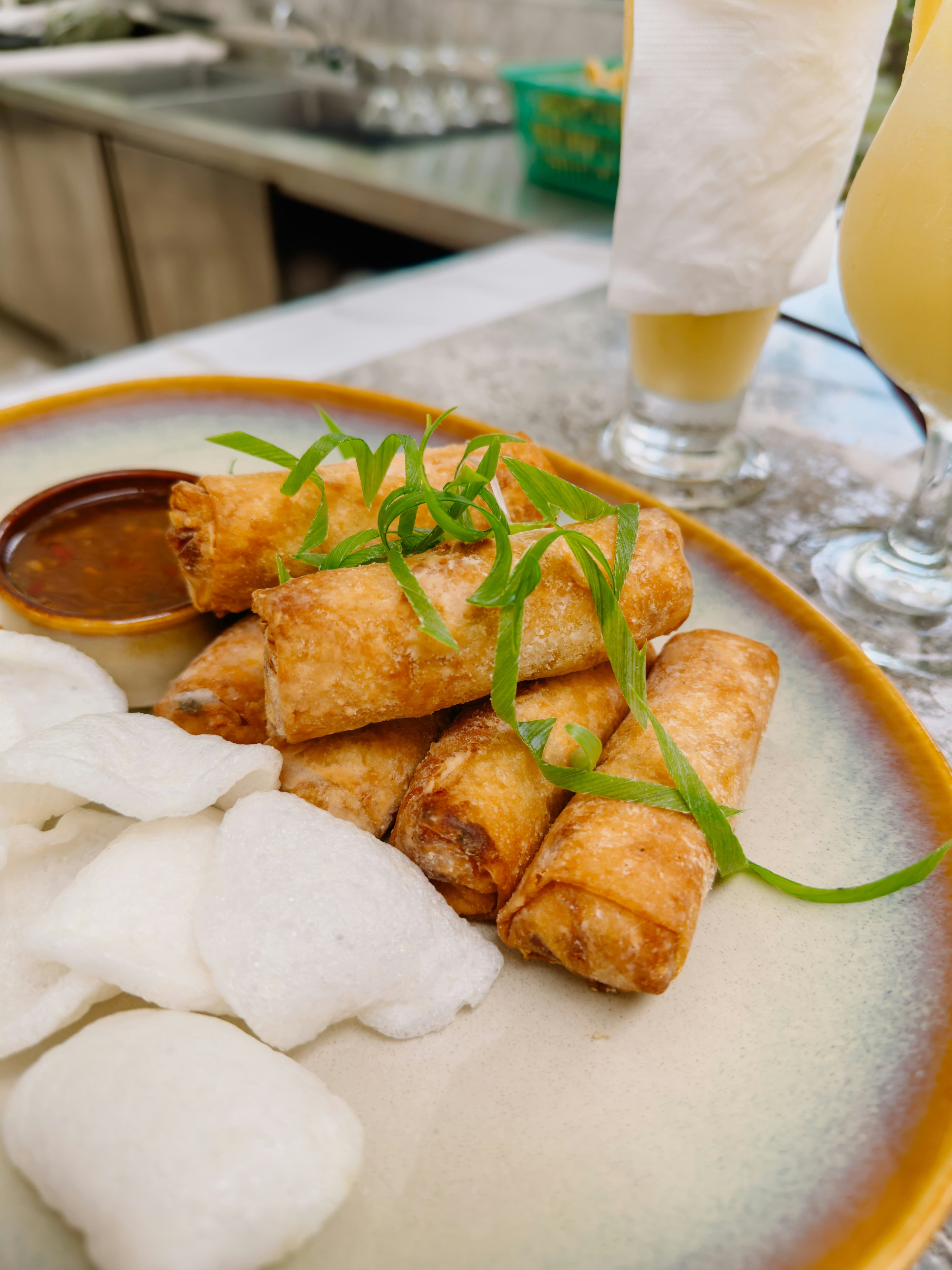 Several spring rolls stacked together and served with dipping sauce.