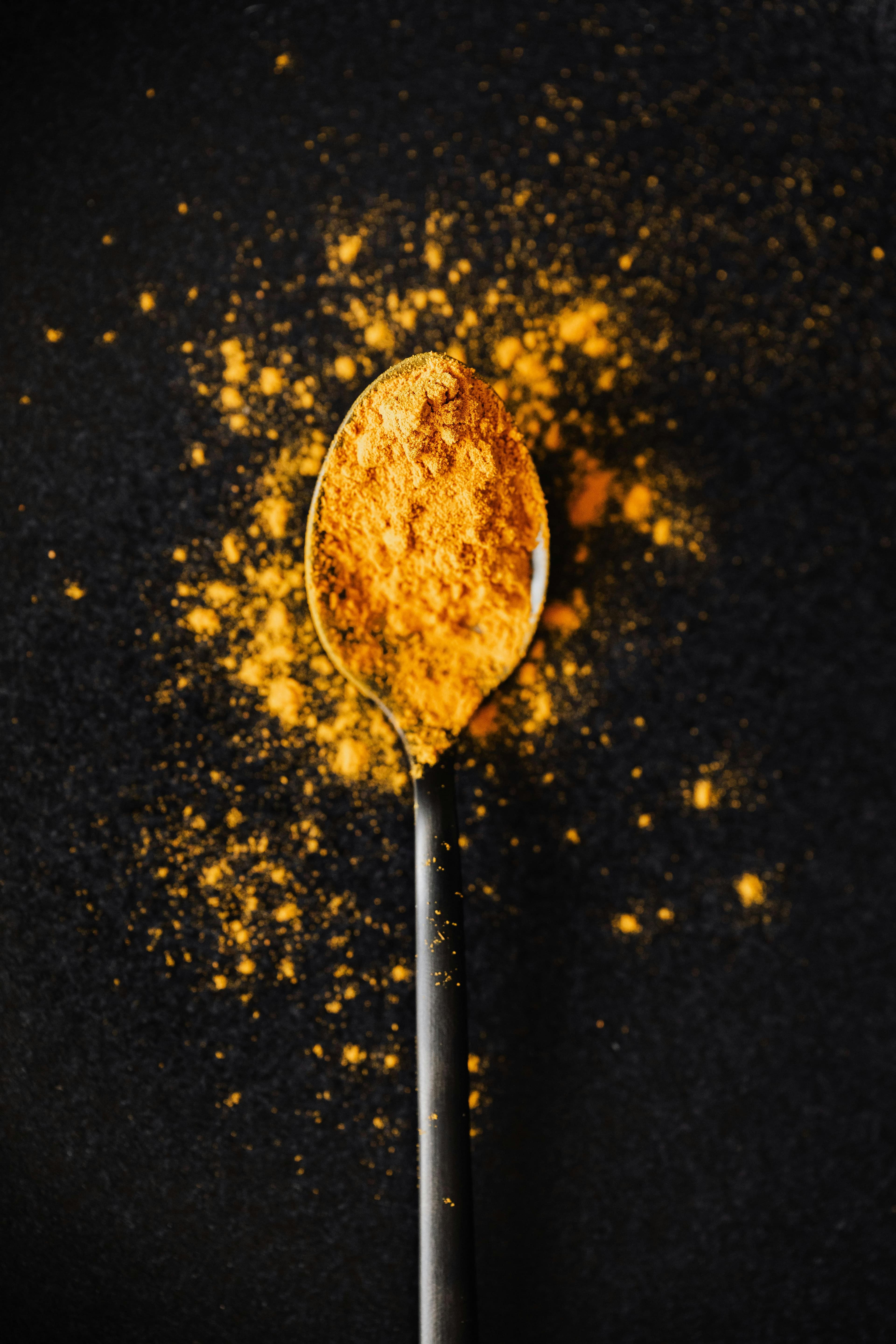 Turmeric powder scooped in a spoon.