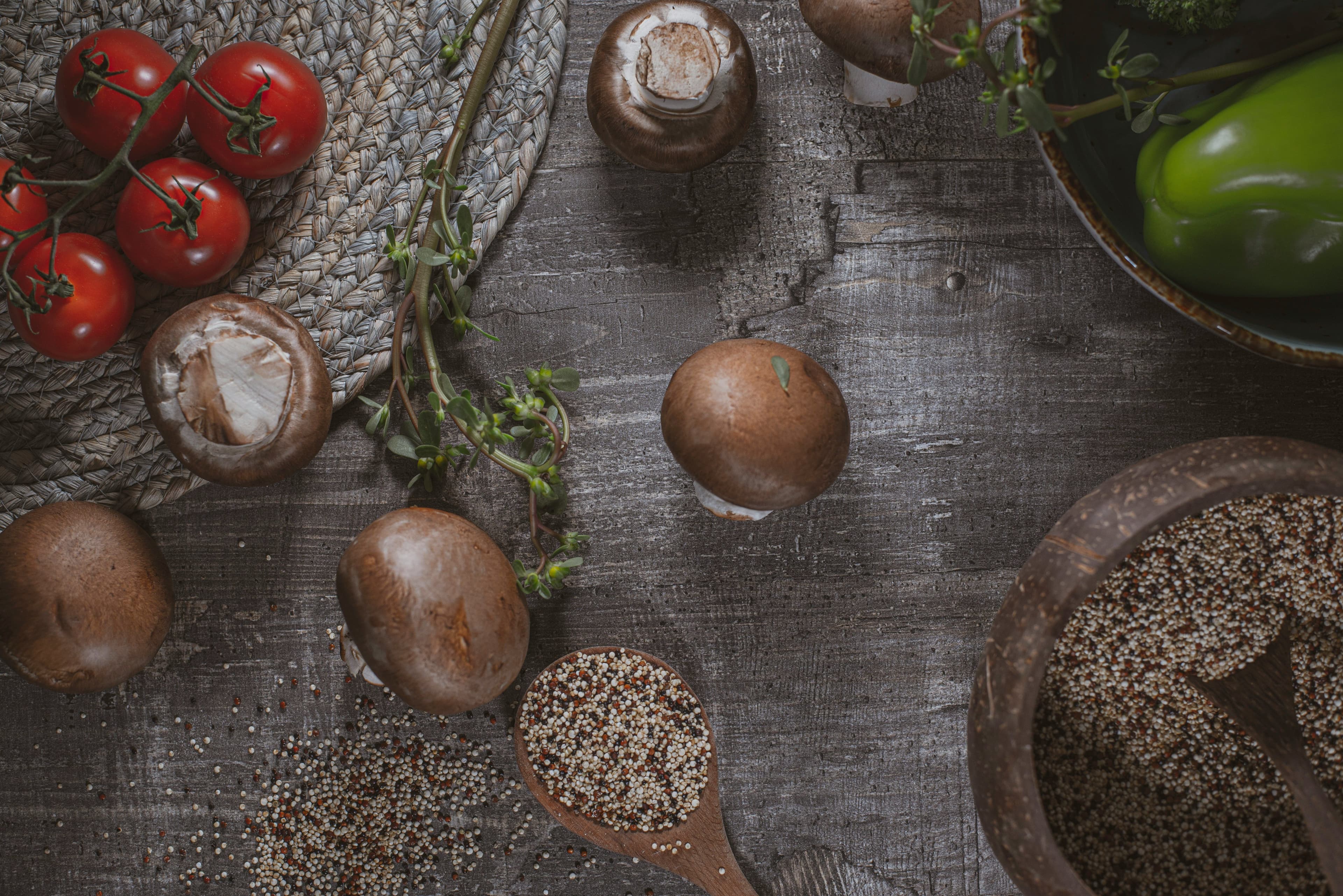 Quinoa seeds placed in a large bowl and a big spoon beside it from which a few seeds have spilled and scattered.