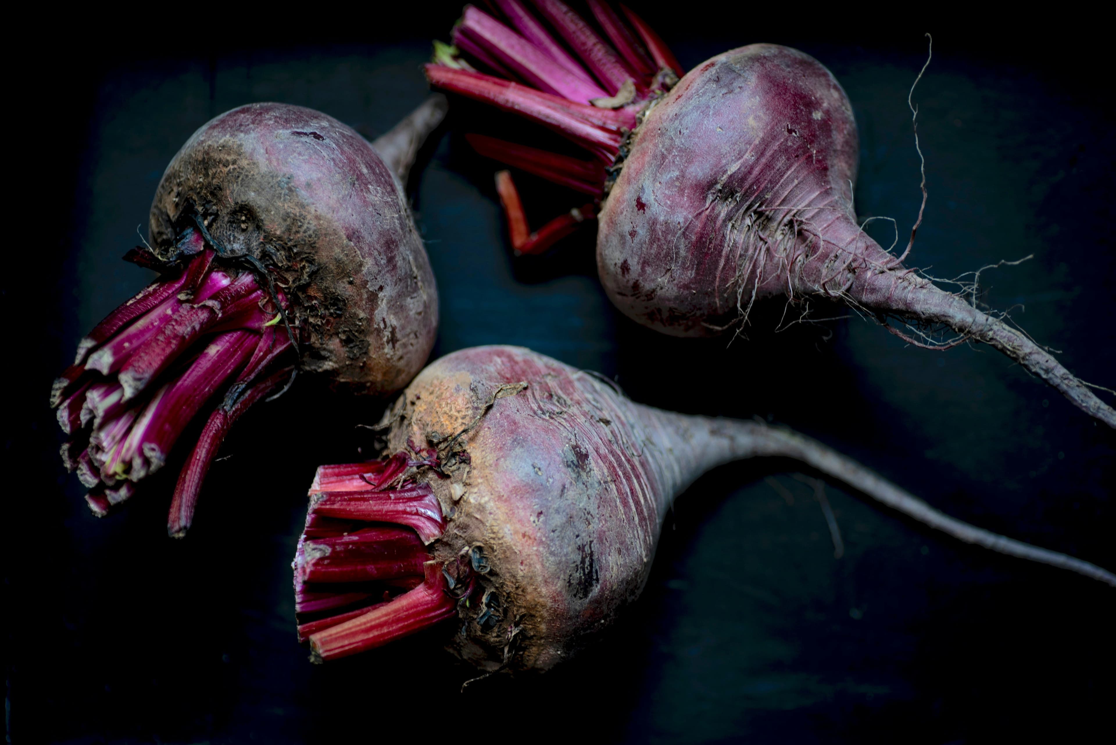 Three whole red beetroots placed beside each other.