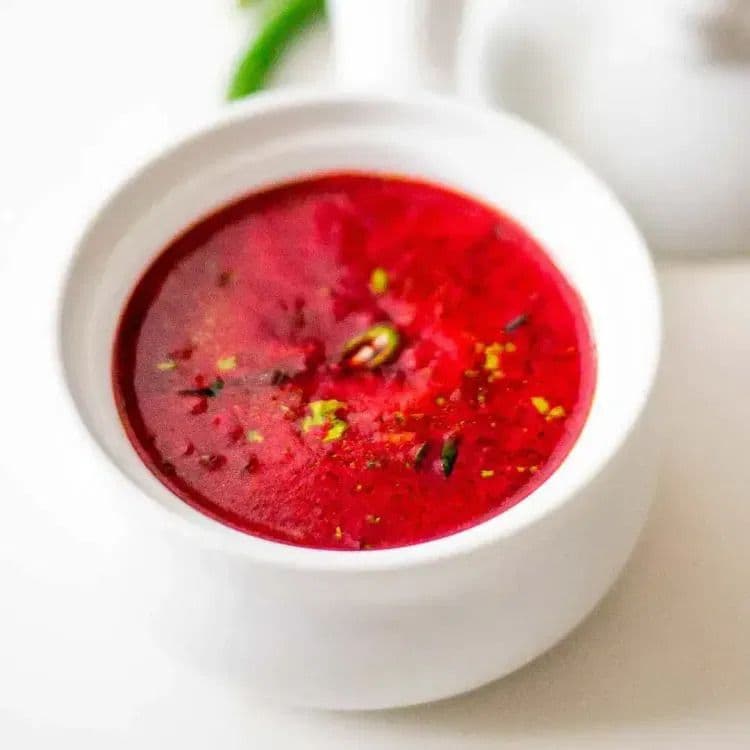 A close-up of freshly cooked beetroot rasam served in a white bowl.