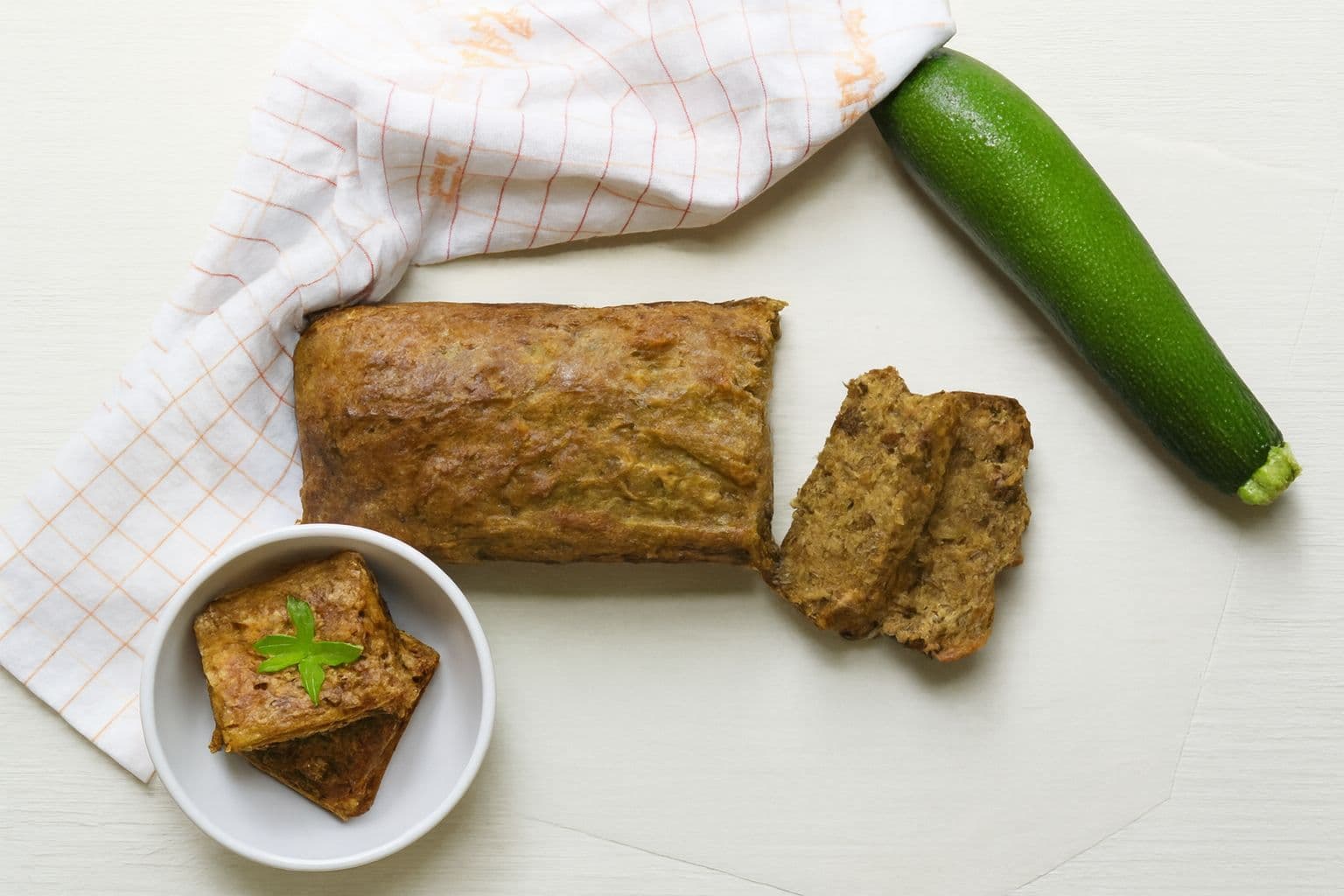 zucchini bread and zucchini brownies set on a table with a whole zucchini lying beside.