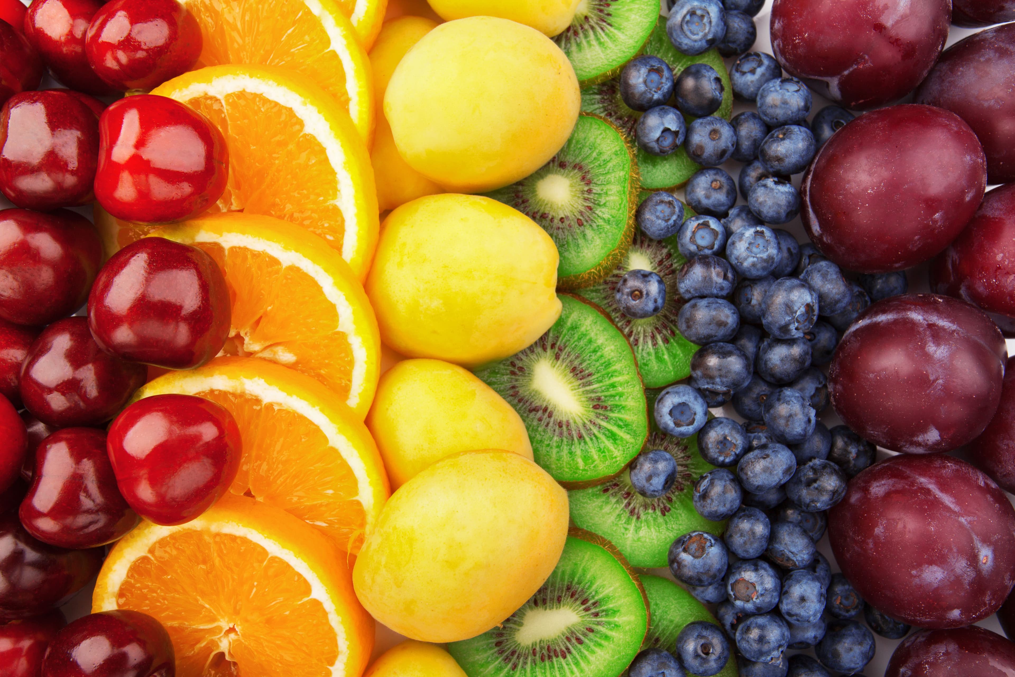 Assortment of fresh colorful fruits like apples, oranges, and bananas arranged in neat rows .