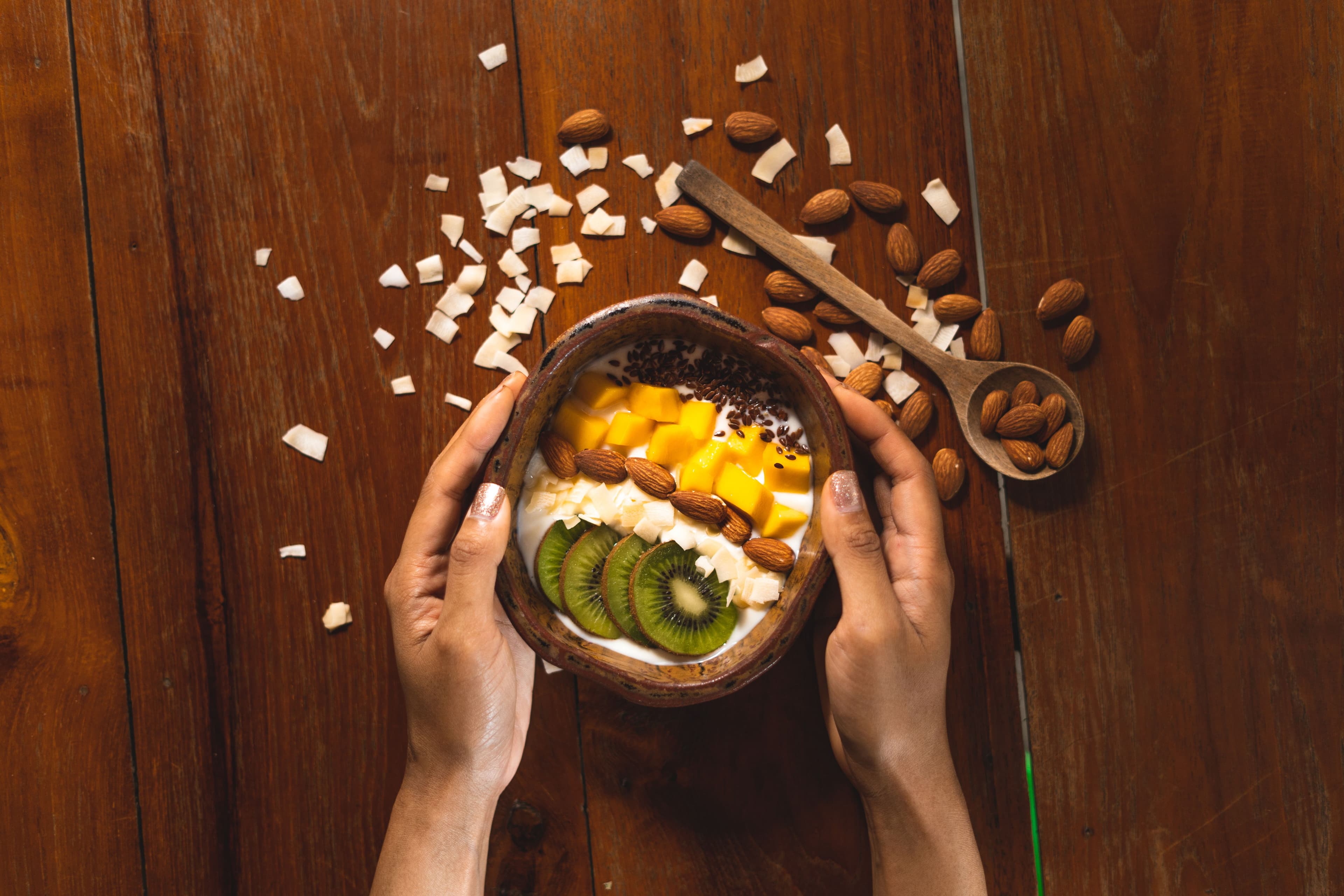 Healthy homemade smoothie bowl with kiwi, mango, almonds, and coconut flakes