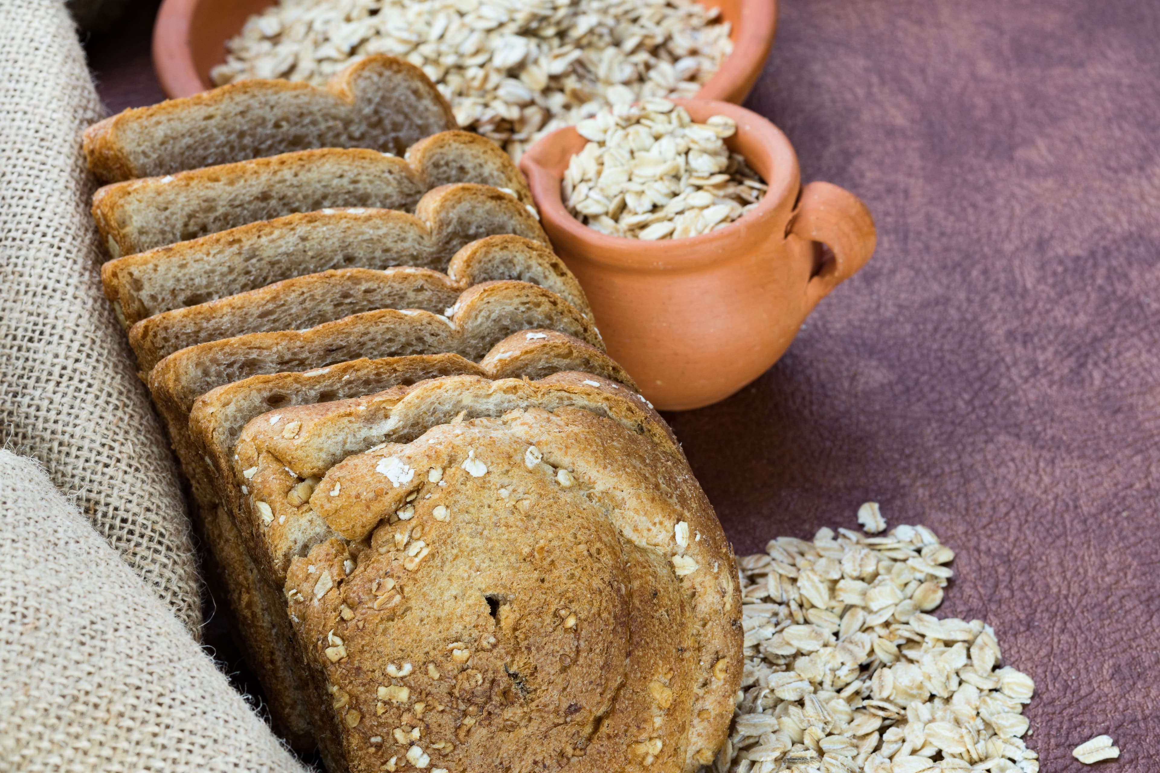 Freshly baked homemade Ezekiel bread loaf on a wooden board, made with sprouted grains, nuts, and wholesome ingredients, that is ideal for clean eating and gut health.
