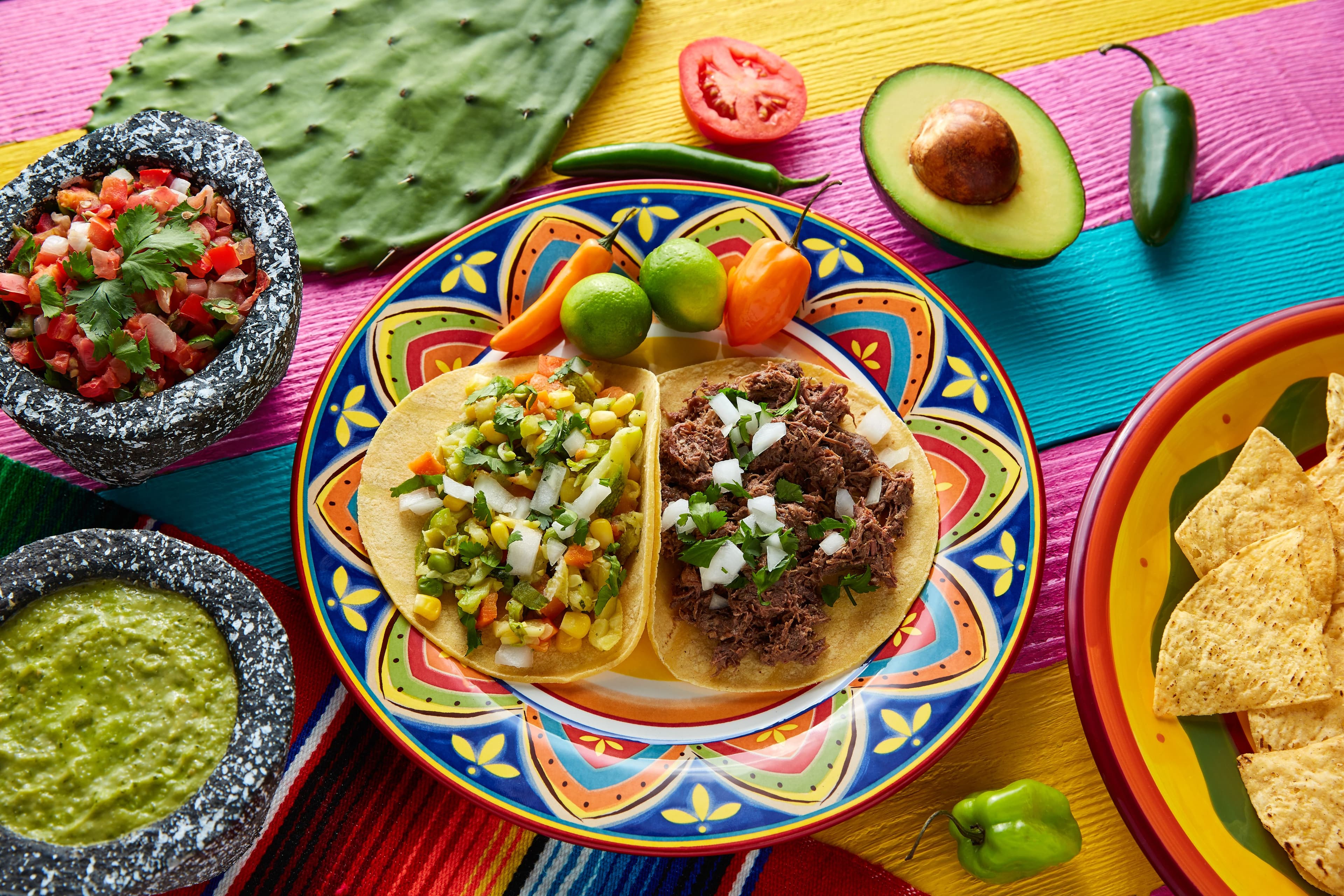 A spread including several classic Mexican Cuisine appetizers including tacos and guacamole.