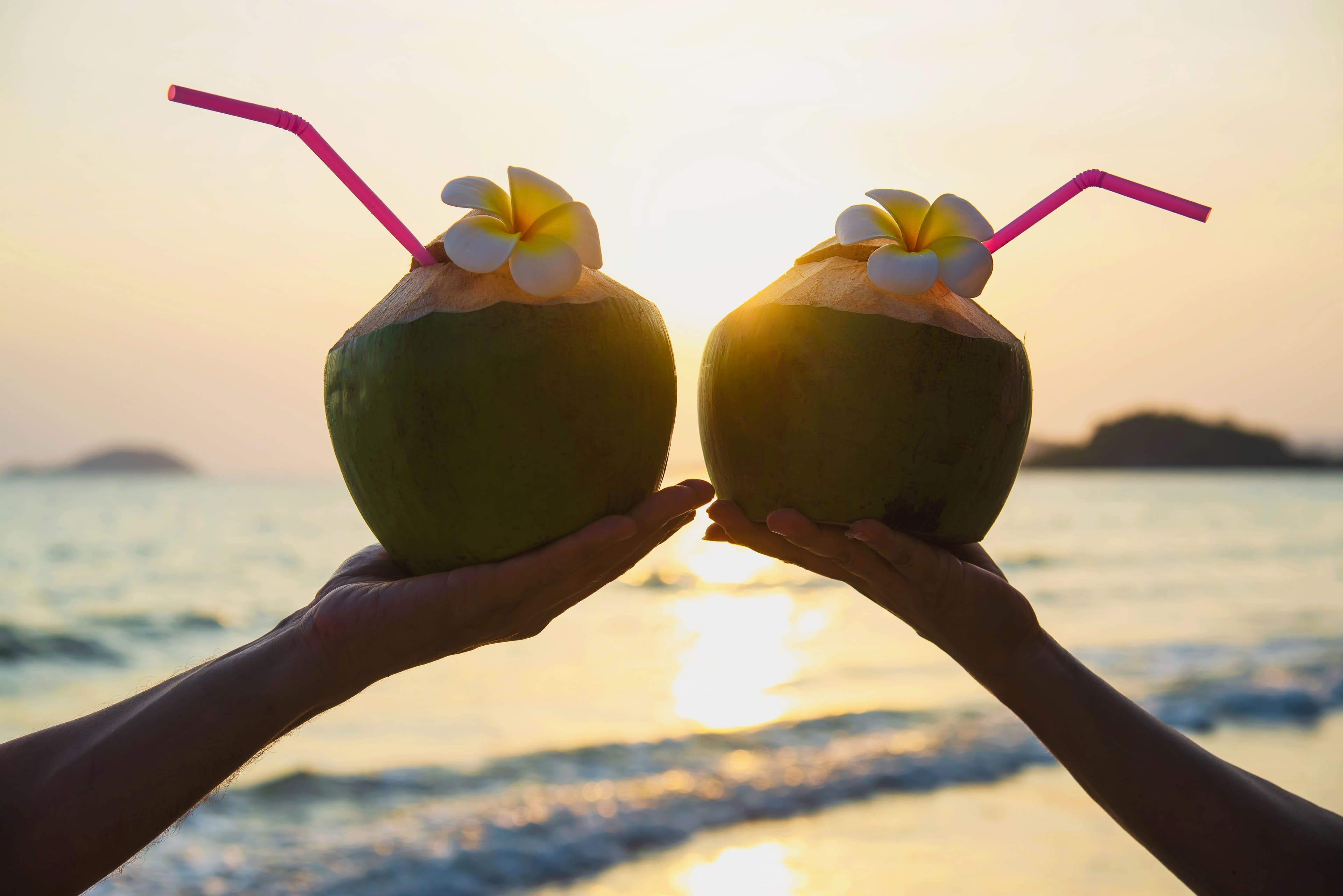 silhouette-fresh-coconut-couples-hands-with-plumeria-decorated-beach-with-sea-wave-tourist-with-fresh-fruit-sea-sand-sun-vacation-concept.jpg
