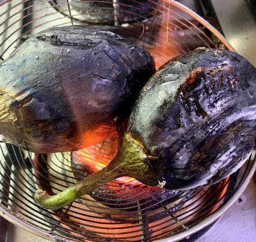 Fire roasting two eggplants on a wire mesh. 