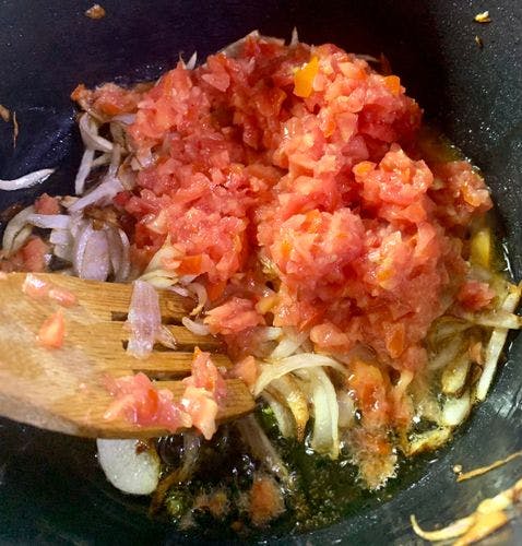 Chopped tomatoes and sliced onions in a wok. 