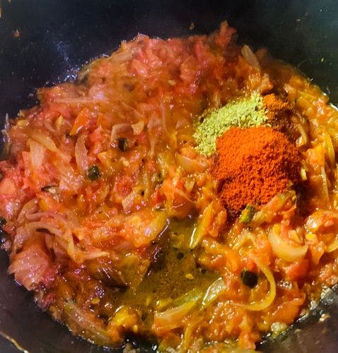 Powdered spices on tempered onions and tomatoes 