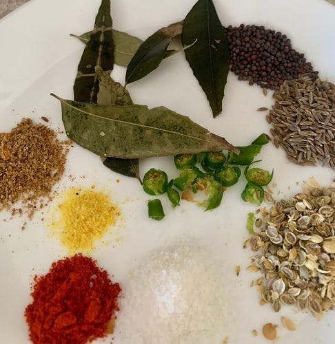 Various powdered and whole spices in a white plate. 