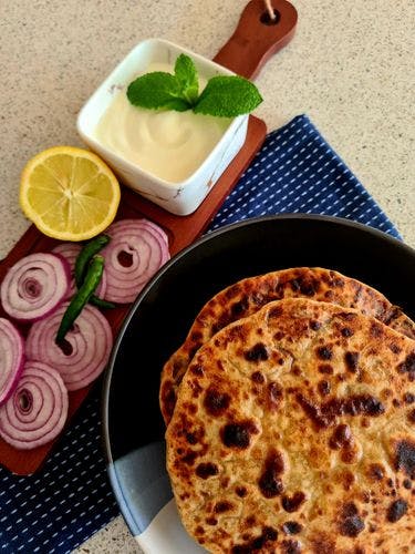 2 parathas served with onions, green chillies, lemon and yogurt.
