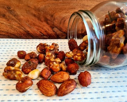 Candied nuts spilling out of a glass jar.