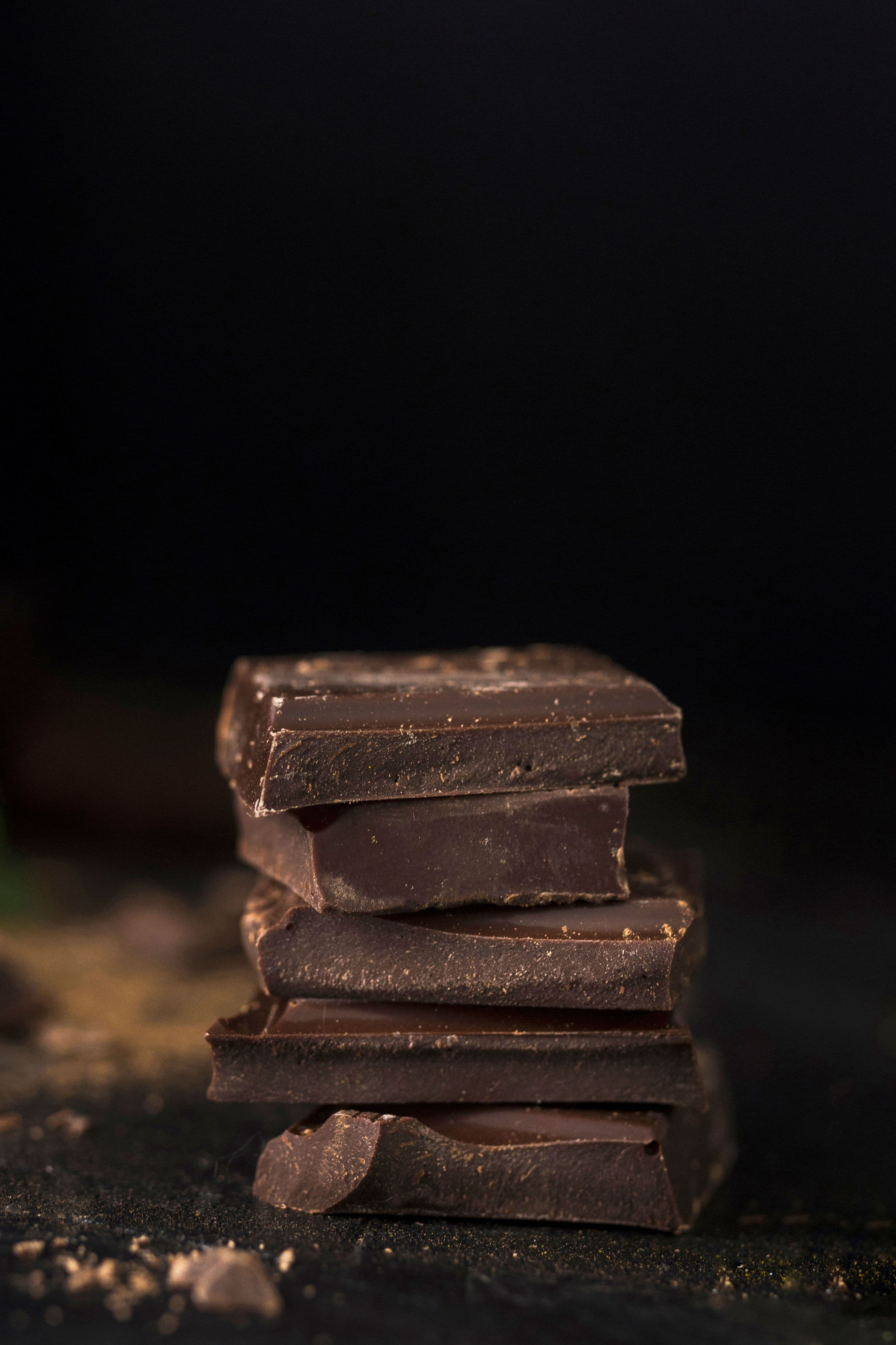 A close-up of stacked dark chocolate pieces with a rich, textured surface.